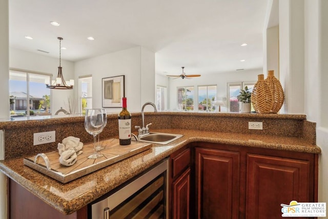 kitchen featuring ceiling fan with notable chandelier, beverage cooler, hanging light fixtures, and sink