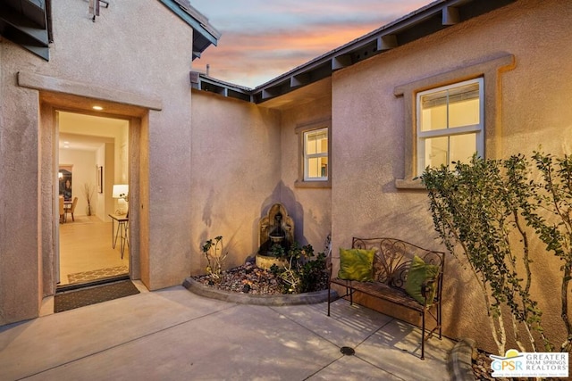 exterior entry at dusk featuring a patio