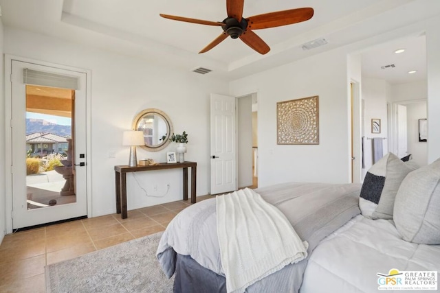 tiled bedroom with ceiling fan and a raised ceiling