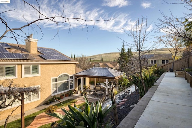 rear view of property with a gazebo, a patio area, and solar panels