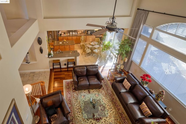 living room featuring a high ceiling, wood-type flooring, and ceiling fan