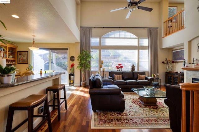 living room featuring ceiling fan, dark hardwood / wood-style flooring, a wealth of natural light, and a fireplace