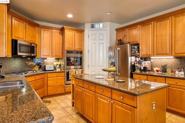 kitchen with dark stone countertops, stainless steel appliances, a center island, light tile patterned floors, and decorative backsplash