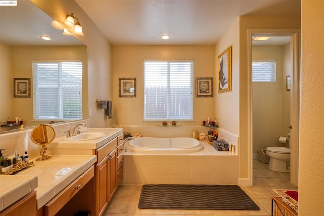 bathroom featuring toilet, a relaxing tiled tub, tile patterned floors, and vanity