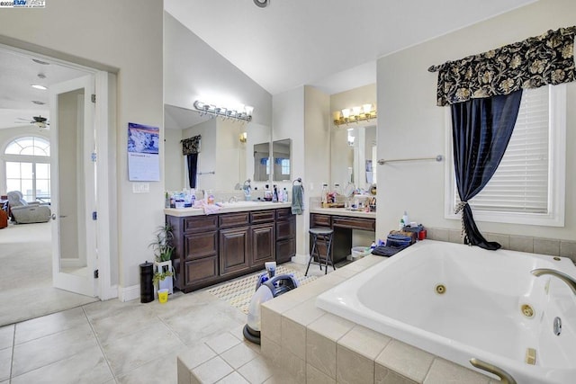 bathroom featuring tiled bath, vaulted ceiling, tile patterned floors, and vanity