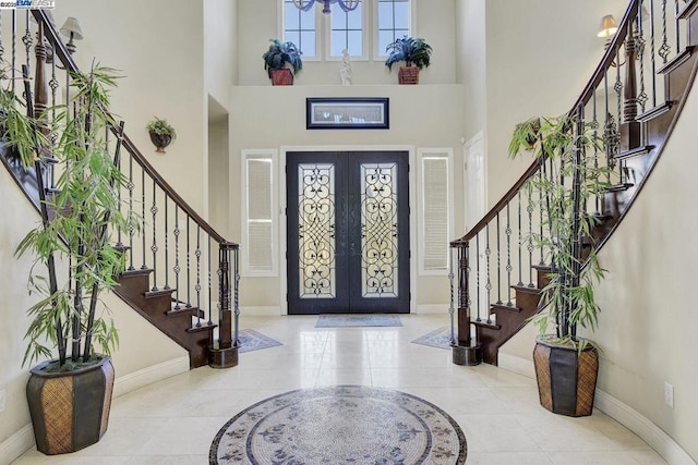 foyer with a towering ceiling, light tile patterned floors, and french doors