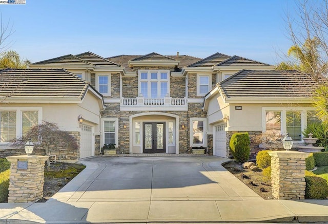 view of front of house featuring a balcony, a garage, and french doors