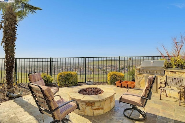 view of patio / terrace featuring exterior kitchen, an outdoor fire pit, and a grill