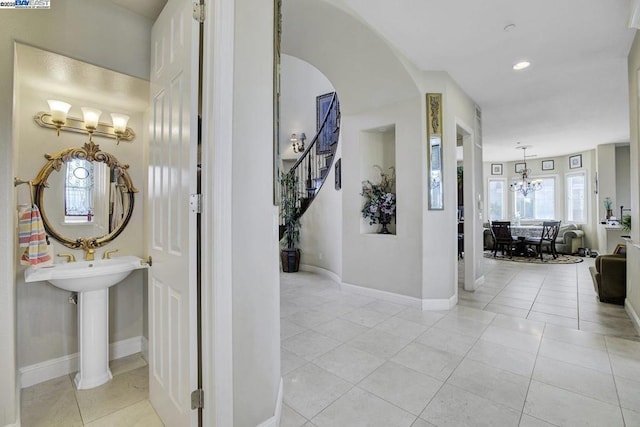 corridor with light tile patterned flooring and a notable chandelier