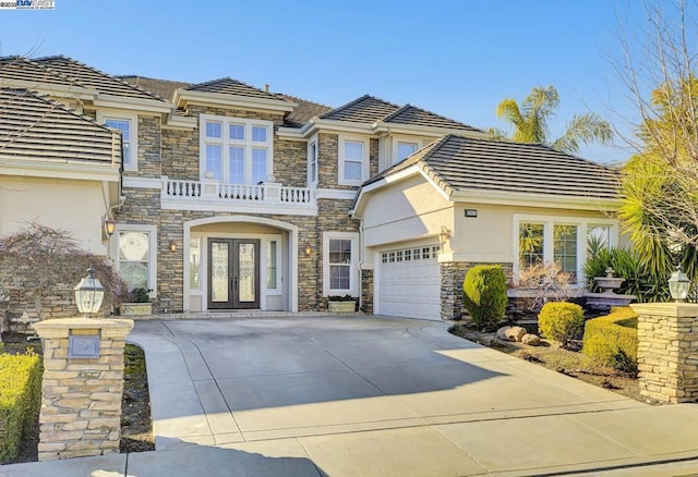 view of front facade with a balcony, french doors, and a garage