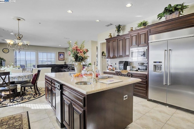 kitchen with sink, pendant lighting, light tile patterned floors, and built in appliances