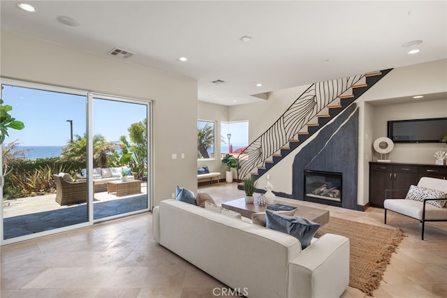 living area featuring recessed lighting, visible vents, a high end fireplace, and stairway