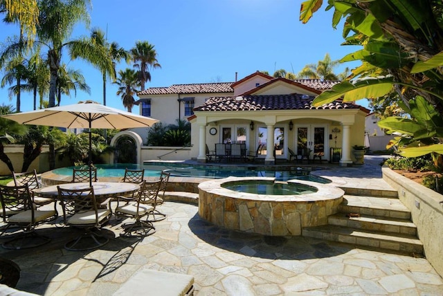 view of swimming pool featuring french doors, a patio area, an outbuilding, and an in ground hot tub