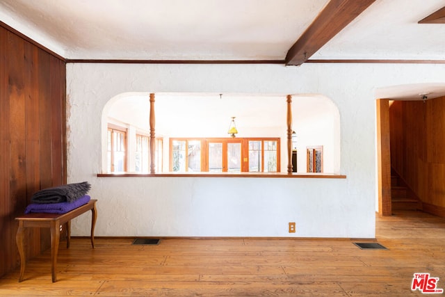 unfurnished room with beam ceiling, light hardwood / wood-style flooring, and a wealth of natural light