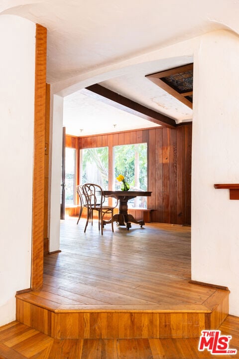 unfurnished dining area with hardwood / wood-style flooring and beamed ceiling