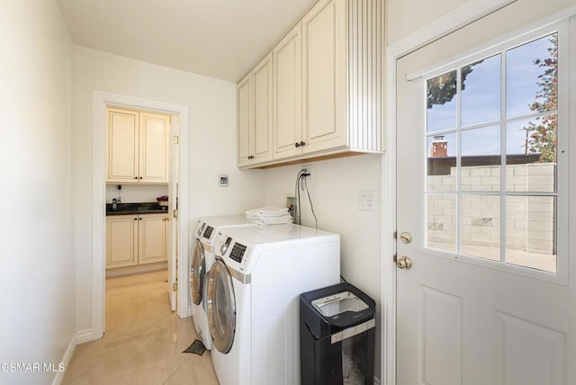 washroom with light tile patterned floors, cabinets, and washer and clothes dryer