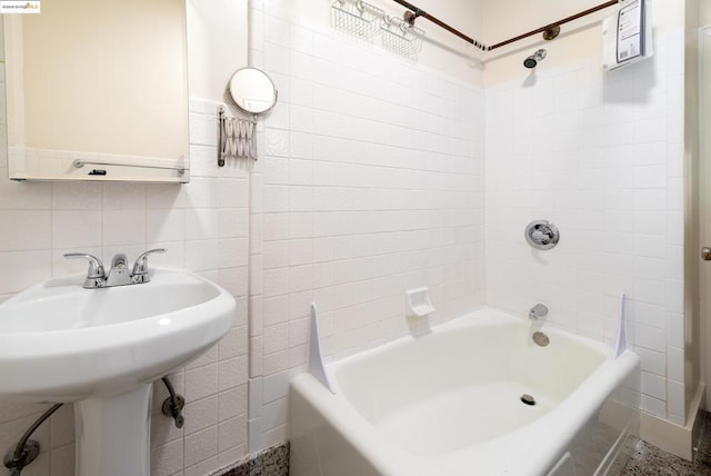 bathroom featuring backsplash, tile walls, and tiled shower / bath