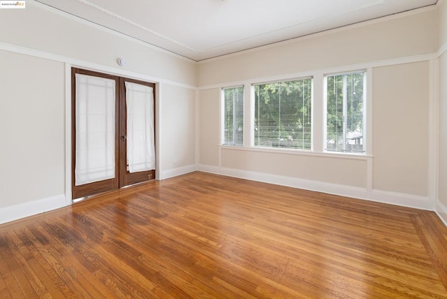 spare room featuring french doors, crown molding, and hardwood / wood-style flooring