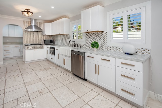 kitchen featuring white cabinetry, wall chimney range hood, appliances with stainless steel finishes, and a wealth of natural light