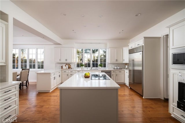 kitchen with stainless steel built in fridge, tasteful backsplash, and a center island