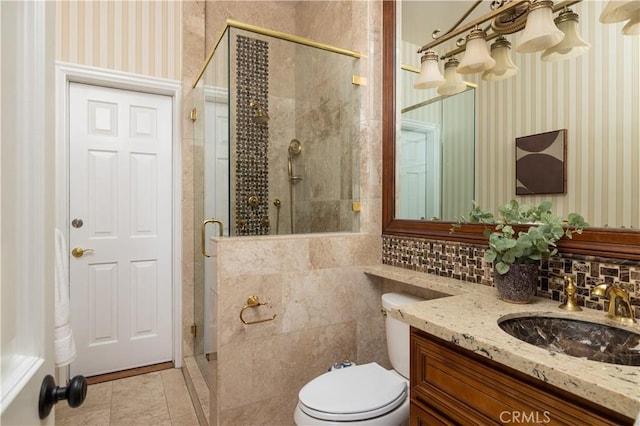 bathroom with toilet, backsplash, tile patterned floors, a shower with shower door, and vanity