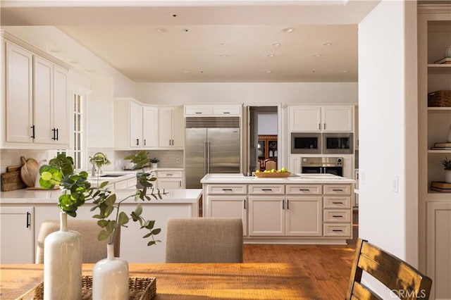 kitchen with sink, white cabinetry, built in appliances, and decorative backsplash