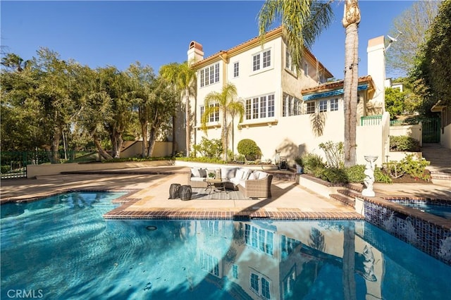 rear view of house with an outdoor hangout area, a fenced in pool, and a patio area