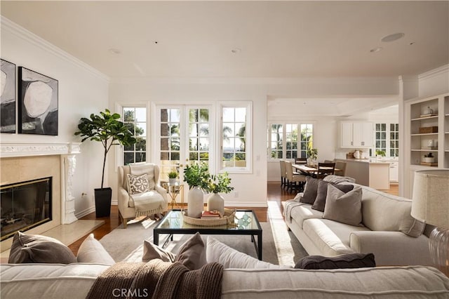 living room featuring a high end fireplace, light hardwood / wood-style floors, and crown molding