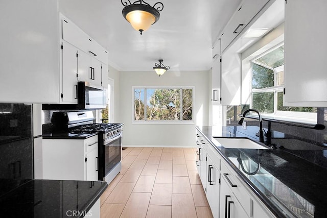 kitchen featuring white cabinetry, stainless steel appliances, dark stone counters, a wealth of natural light, and sink