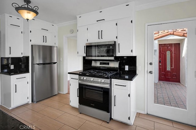 kitchen with tasteful backsplash, white cabinets, appliances with stainless steel finishes, and crown molding