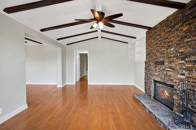 unfurnished living room featuring built in shelves, vaulted ceiling with beams, a fireplace, light wood-type flooring, and ceiling fan