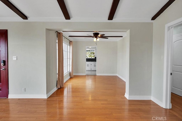 empty room featuring beam ceiling, light wood-type flooring, ornamental molding, and ceiling fan