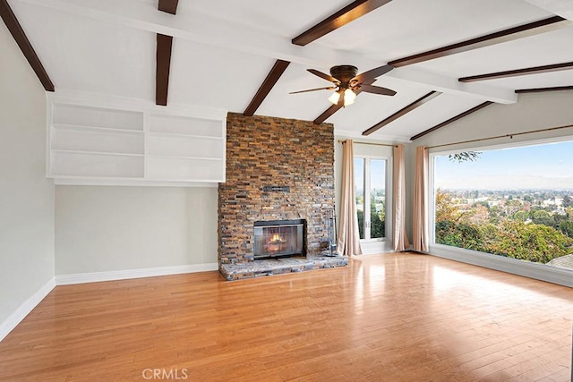 unfurnished living room with ceiling fan, lofted ceiling with beams, a fireplace, and light hardwood / wood-style flooring