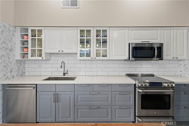 kitchen with white cabinetry, stainless steel appliances, tasteful backsplash, sink, and gray cabinets