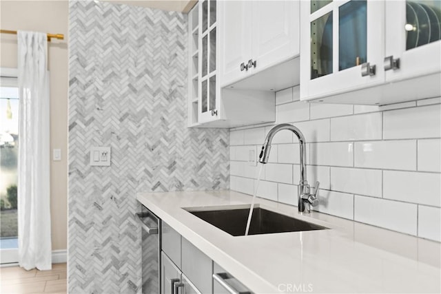 kitchen featuring tasteful backsplash, dishwasher, sink, and white cabinets