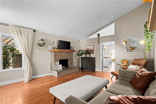 living room with vaulted ceiling, a brick fireplace, and hardwood / wood-style flooring