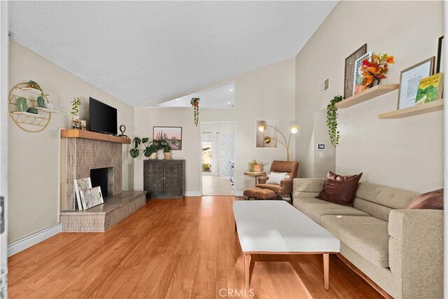 living room with hardwood / wood-style flooring, lofted ceiling, and a fireplace