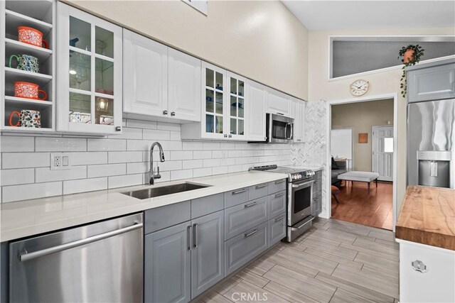 kitchen featuring white cabinetry, gray cabinets, appliances with stainless steel finishes, tasteful backsplash, and sink