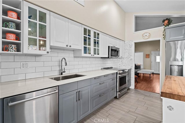 kitchen with sink, gray cabinetry, stainless steel appliances, decorative backsplash, and white cabinets