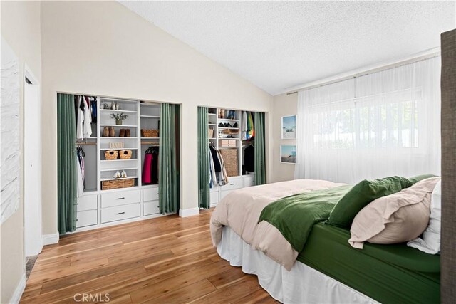 bedroom featuring hardwood / wood-style floors, lofted ceiling, and a textured ceiling