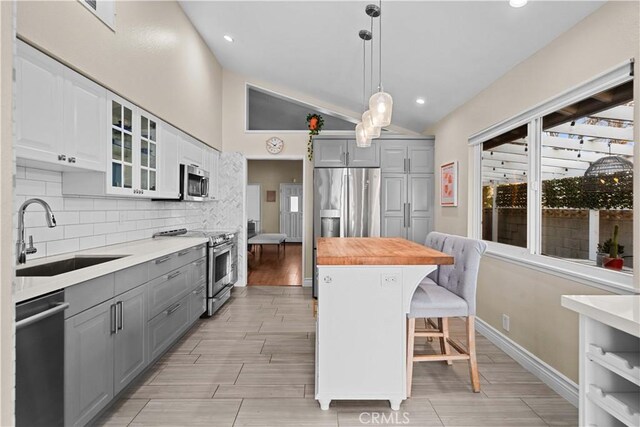 kitchen featuring butcher block counters, stainless steel appliances, decorative backsplash, sink, and gray cabinets