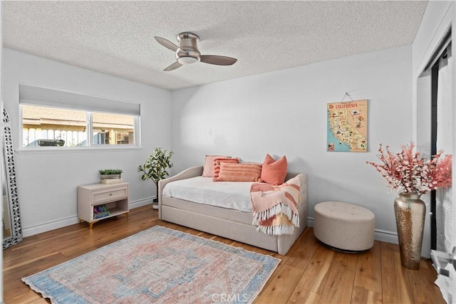 bedroom featuring ceiling fan, wood-type flooring, and a textured ceiling