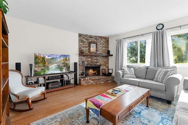 living room with a textured ceiling, a brick fireplace, and wood-type flooring