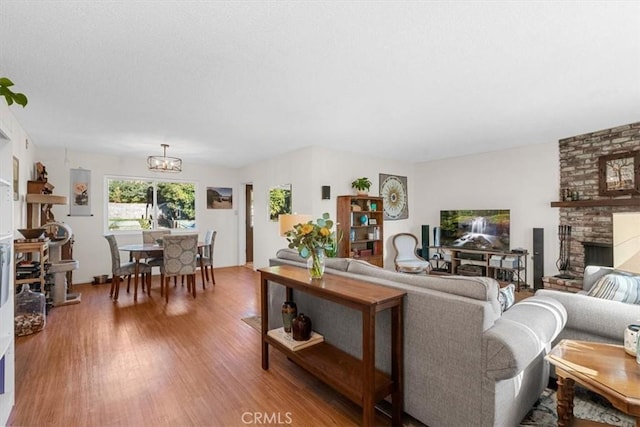 living room featuring a brick fireplace, an inviting chandelier, and hardwood / wood-style flooring