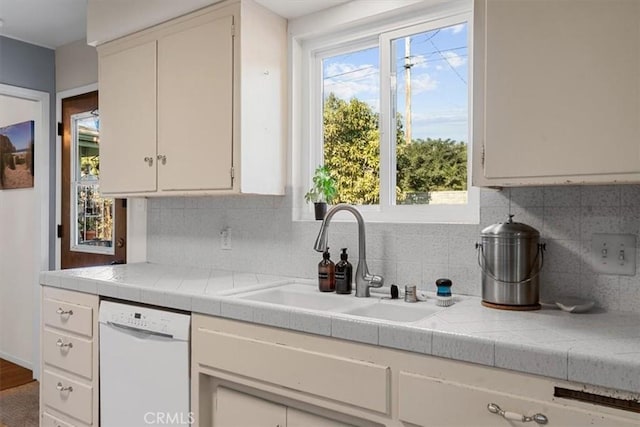 kitchen with white dishwasher, decorative backsplash, and sink