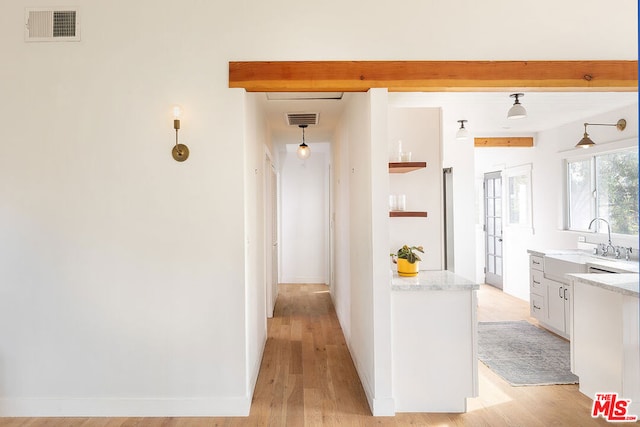 hallway featuring sink, beam ceiling, and light wood-type flooring