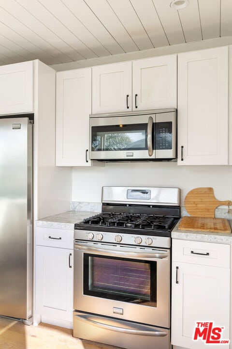 kitchen featuring white cabinets, appliances with stainless steel finishes, and light hardwood / wood-style flooring