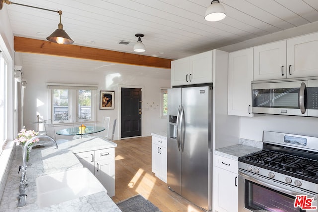 kitchen with light hardwood / wood-style floors, hanging light fixtures, light stone countertops, stainless steel appliances, and white cabinets