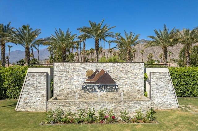 community / neighborhood sign with a yard and a mountain view