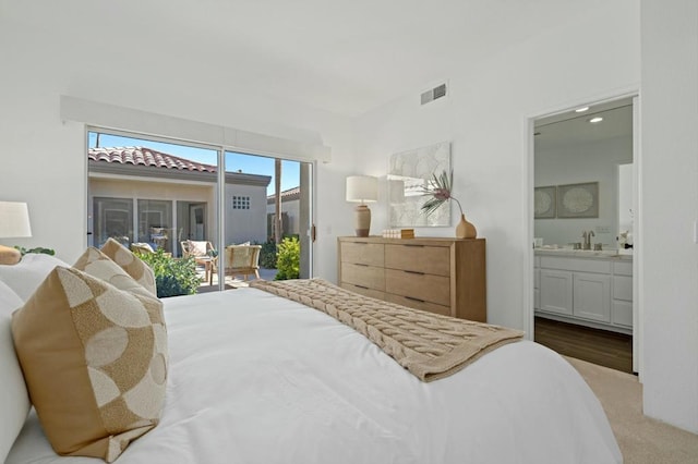 carpeted bedroom with access to outside, ensuite bath, and sink